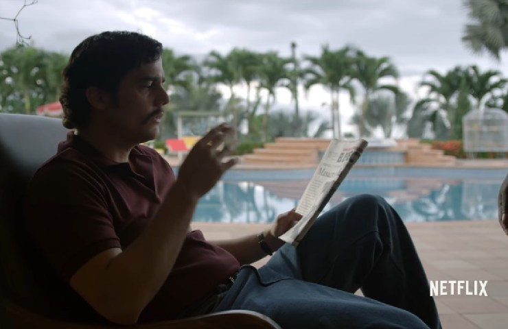 L'attore che interpreta Pablo Escobar della serie Narcos che legge il giornale seduto vicino alla piscina