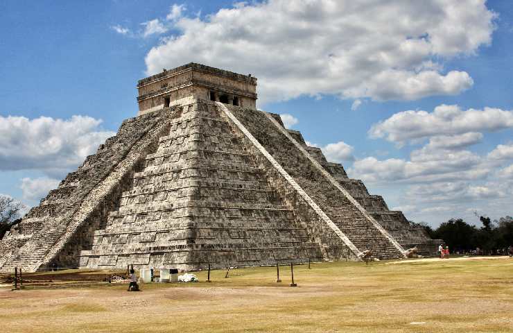 Piramide di Kukulkcan che si staglia su un cielo nuvoloso sopra a una distesa arida