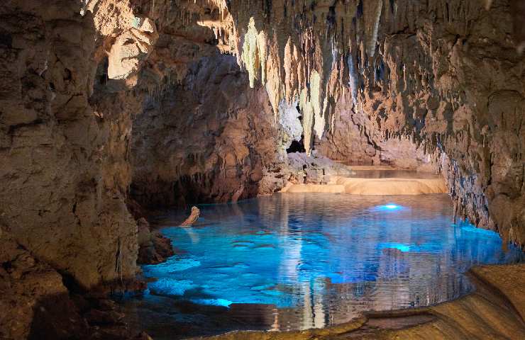 Grotte calcaree a punta con all'interno un fiume dall'acqua blu e cristallina