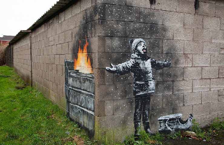 Graffito di Banksy in cui un bambino sta con mani spalancate mentre cerca con la bocca fiocchi di cenere da un bidone in fiamme