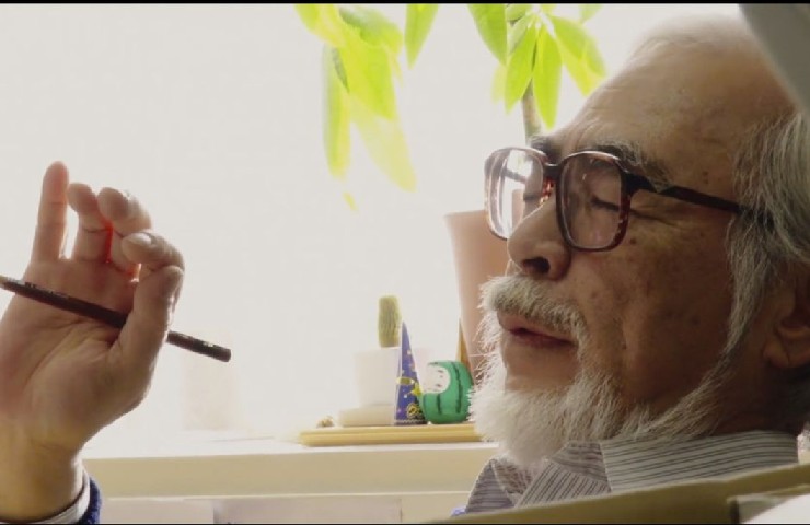 Regista Miyazaki che pensa ad occhi chiusi e con una penna in mano per disegnare