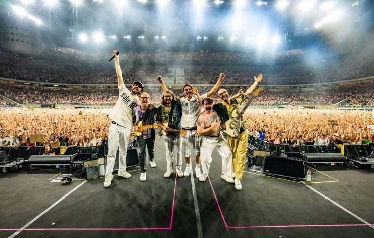 La band dei Pinguini Tattici Nucleari sopra al palco di San Siro, di spalle a tutti i loro fan sullo sfondo