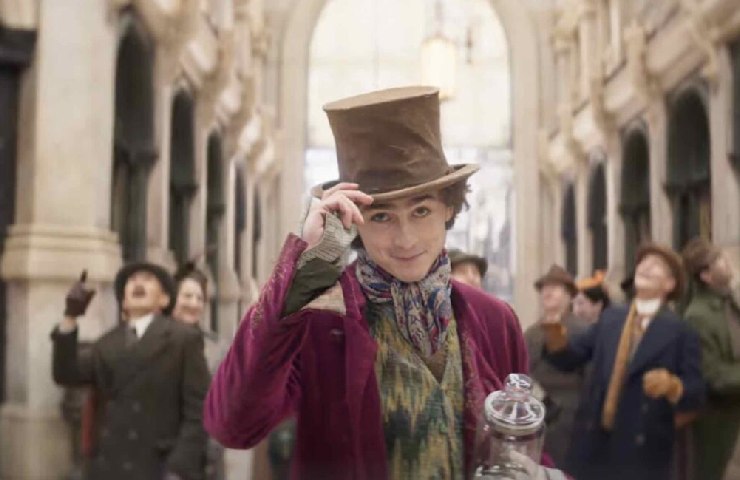 Scena dal film Wonka con Chalamet nei panni di Wonka che balla alzando il suo cilindro con altri ballerini dietro