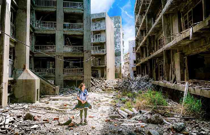 Bambina tra le rovine di una città fantasma dai palazzi di cemento