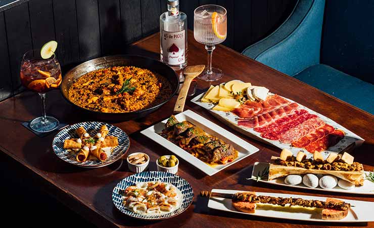 un tavolo pieno di tapas spagnole, tra cui paella, salumi e formaggi