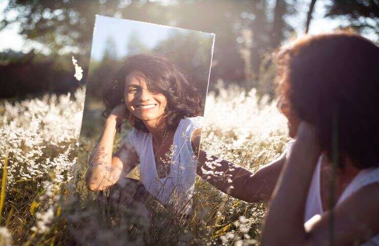 donna sorridente che si guarda allo specchio