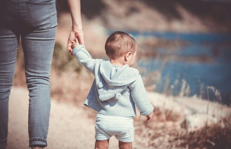 Bambino che cammina dando la mano alla mamma