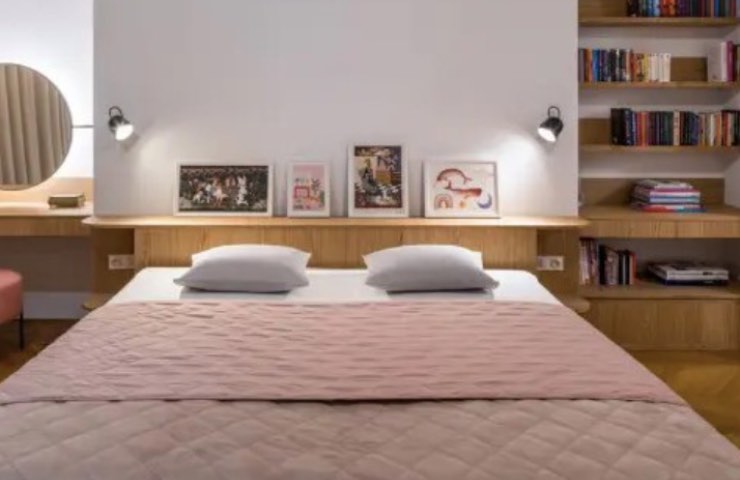 Letto matrimoniale con coperta rosa in camera dalla periti bianche