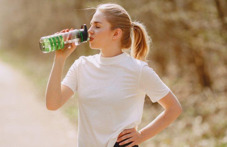 Ragazza beve acqua dalla bottiglia 