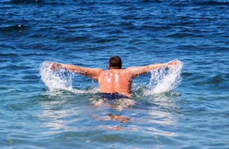 Uomo nuota nell'acqua del mare 